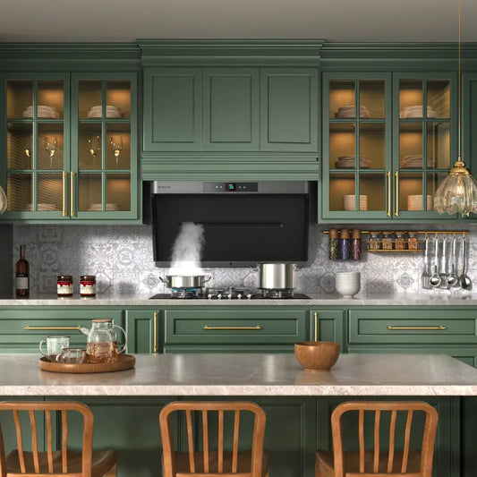 Elegant sage green kitchen with glass cabinet doors, marble countertops, and a black range hood capturing steam from cooking