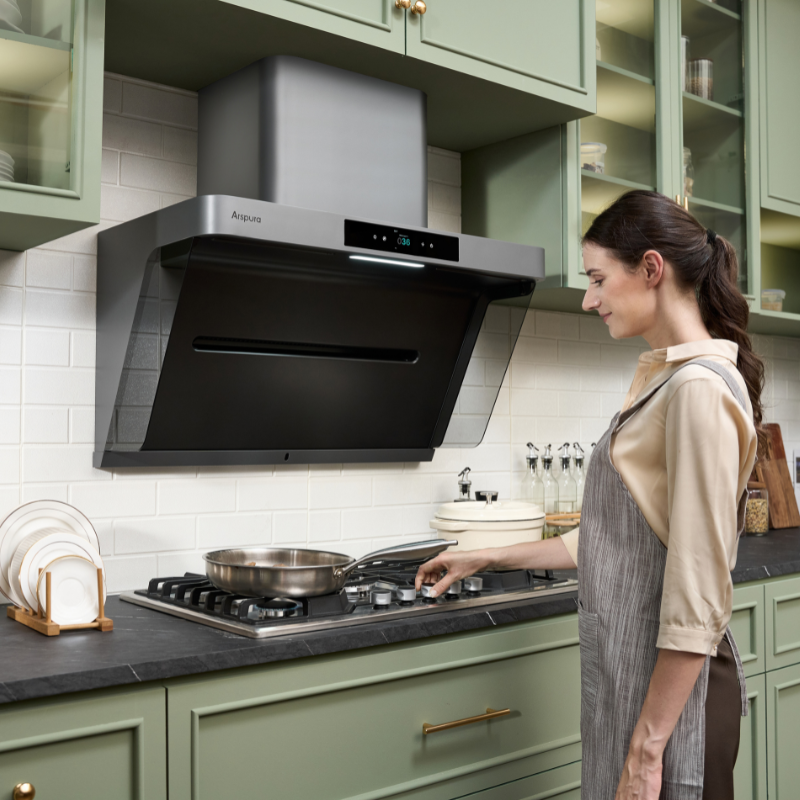 Woman cooking under Anapura kitchen range hood with digital display