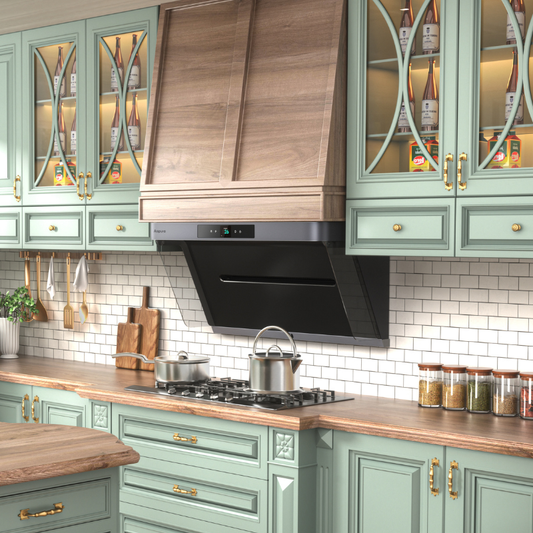 Modern kitchen with sage green cabinets, decorative glass doors with geometric patterns, wood-look chimney cover extending to ceiling above black angled range hood, white subway tile backsplash, and wooden countertops with cutting boards